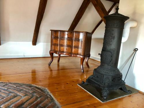 a black stove in a room with a wooden floor at The Houses of History - anno 1830 in Tihany