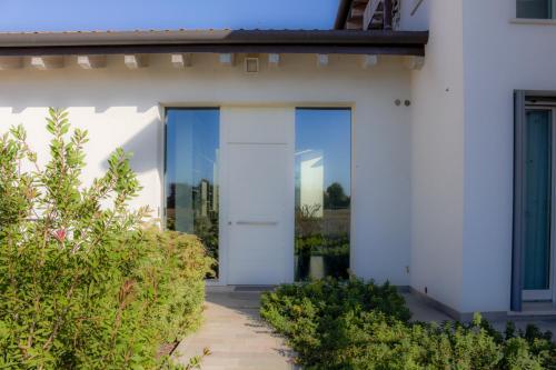 a white house with glass doors and bushes at Ca' Belvedere in Sant'Elena di Silea