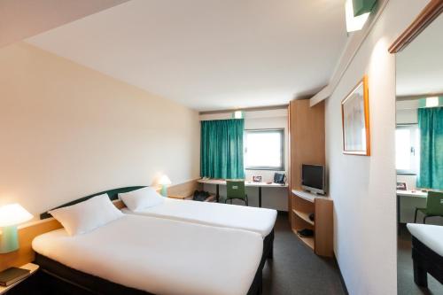 um quarto de hotel com duas camas e uma secretária em ibis Blois Vallée Maillard em Blois