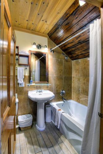a bathroom with a tub and a sink and a bath tub at Auberge Baker in Chateau Richer