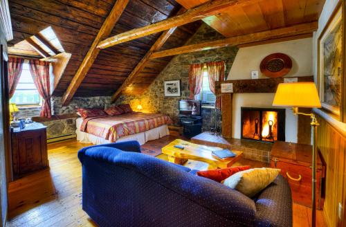 a living room with a couch and a bed and a fireplace at Auberge Baker in Chateau Richer