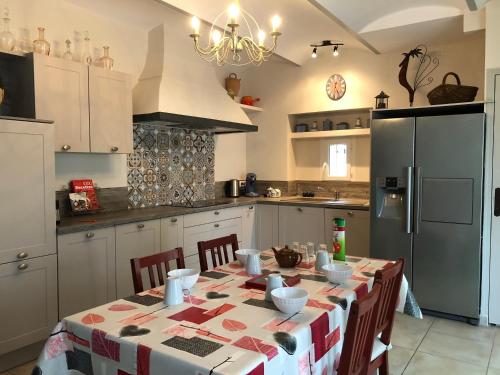 uma cozinha com uma mesa e um frigorífico em Mas Du Petit Chemin em Caux