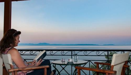a woman sitting in a chair reading a book on a balcony at Polichni in Leonidion