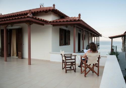 a woman sitting at a table on the porch of a house at Polichni in Leonidion