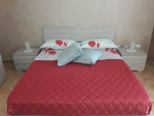 a bed with a red comforter and pillows at Casa Rosy.S in Pozzuoli