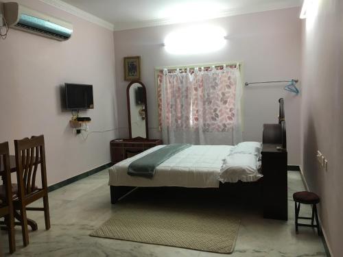 ein Schlafzimmer mit einem Bett, einer Kommode und einem TV in der Unterkunft Pleasant Stay in Tiruchchirāppalli
