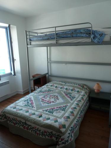 a bedroom with a bunk bed with a quilt on it at la maison de vincente in Arzon