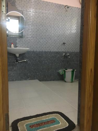 a bathroom with a sink and a mirror and a tile wall at Pleasant Stay in Tiruchirappalli
