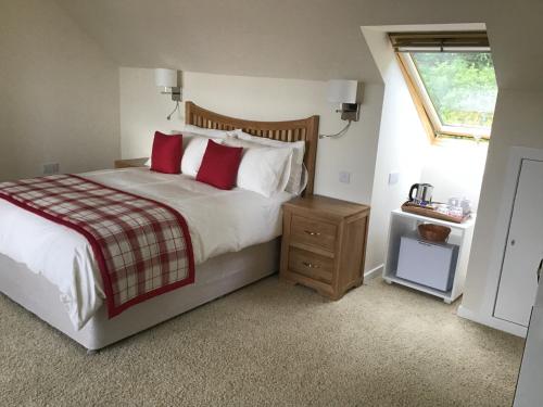 a bedroom with a bed with red pillows and a window at Gramarvin B&B in Oban