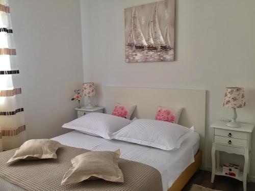 a bedroom with a bed with white sheets and pink pillows at Apartman Dujmović in Split