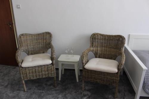 two wicker chairs and a table with a wine glass at Hotel Amadeus in České Budějovice
