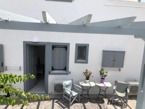 a patio with chairs and tables and a white wall at Black Coast Santorini in Perivolos
