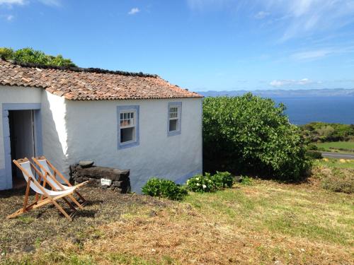 a white house with two chairs in front of it at Casa do Alto in Santo António