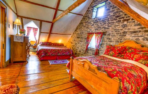 a bedroom with two beds and a stone wall at Auberge Baker in Chateau Richer