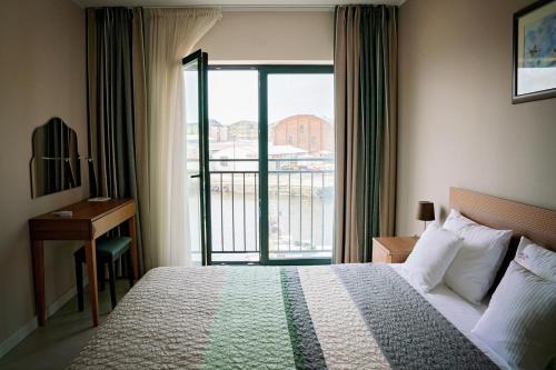 ウストカにあるDeluxe by Maximusのベッドとバルコニー付きのホテルルーム