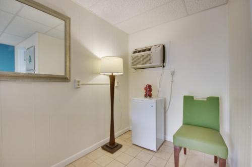 Habitación con silla verde, espejo y nevera. en White Marlin Inn en Ocean City