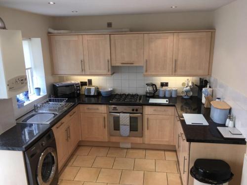 a kitchen with wooden cabinets and a stove top oven at Stunning House in Felinheli Marina in Y Felinheli