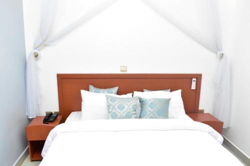a bed with white sheets and blue pillows at Lebanon Hotel in Kigali