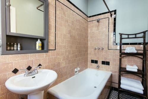 a bathroom with a sink and a tub and a mirror at Broadlind Hotel in Long Beach