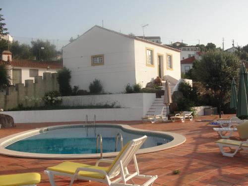 a swimming pool with chairs and a house at Quinta do Belo-Ver Turismo de Habitacao in Belver