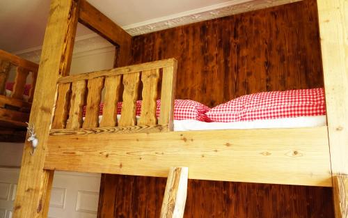 a wooden bunk bed with red pillows on it at Adventure Hostel Interlaken in Interlaken