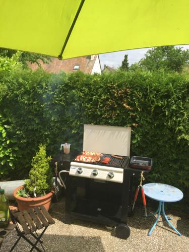 a barbecue grill sitting on a patio under a green umbrella at Au Nid de Tillé in Tillé