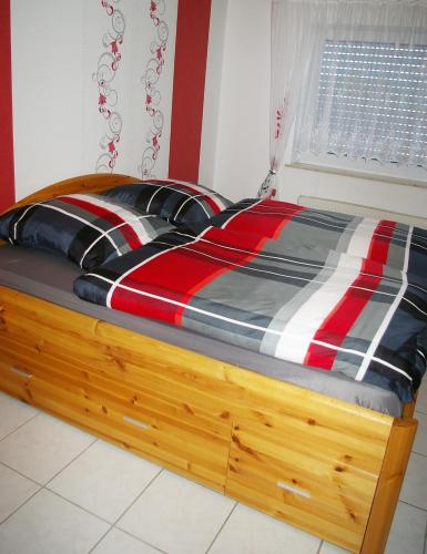 a bed with a red and black comforter in a bedroom at fewogriebelschied in Griebelschied