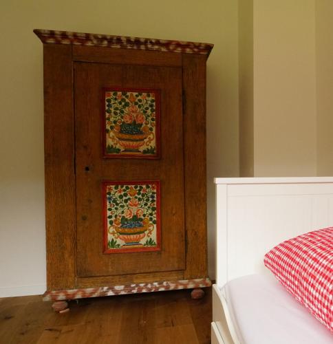 a wooden cabinet with two pictures on it next to a bed at Adventure Hostel Interlaken in Interlaken