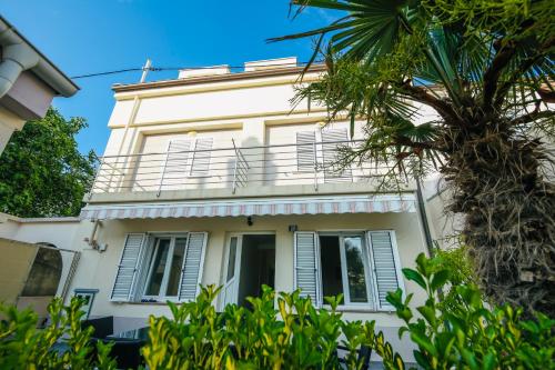 a white house with a balcony and a palm tree at Skunca’s house in Novalja