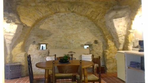 une salle à manger avec une table et un mur en pierre dans l'établissement Le Pigeonnier du Château, à Saint-Victor-de-Malcap