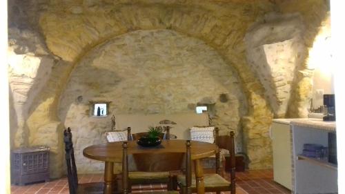 ein Esszimmer mit einem Tisch und einer Steinmauer in der Unterkunft Le Pigeonnier du Château in Saint-Victor-de-Malcap