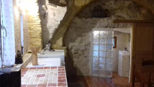 La salle de bains est pourvue d'une baignoire et d'un mur en pierre. dans l'établissement Le Pigeonnier du Château, à Saint-Victor-de-Malcap