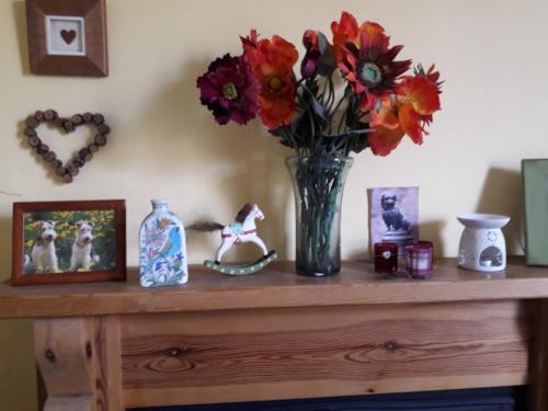 a wooden table with a vase of flowers and pictures at Strome Lodge in Inverness