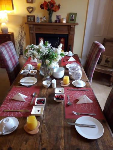 una mesa de madera con platos y utensilios. en Strome Lodge, en Inverness