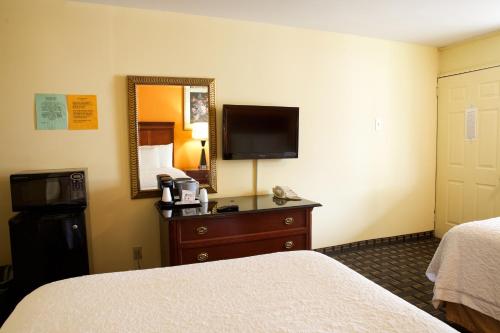 a hotel room with a bed and a dresser with a television at Highlander Motel in Athens