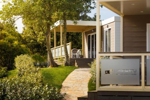 a house with a porch and a chair on the porch at Mobile Homes - FKK Nudist Camping Solaris in Poreč