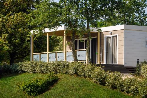 a small house with a tree in the yard at Mobile Homes - FKK Nudist Camping Solaris in Poreč