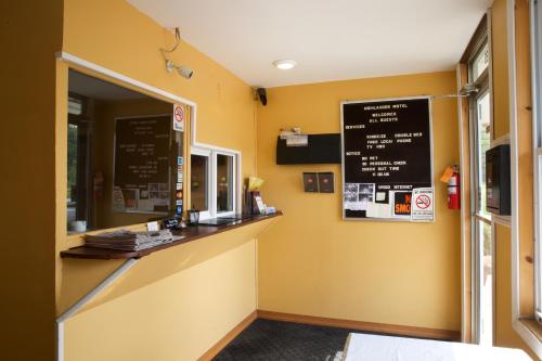 a restaurant with yellow walls and a counter with a chalkboard at Highlander Motel in Athens