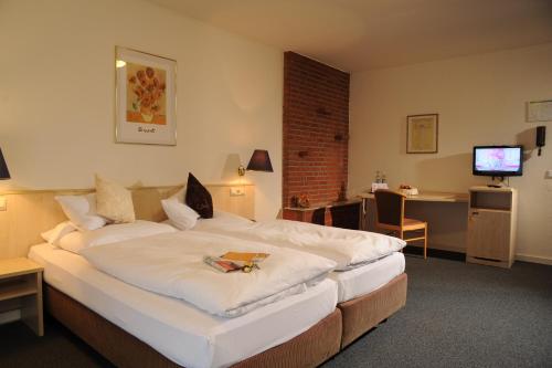 デュッセルドルフにあるエア ホテル ヴァルトブルクの大きなベッドとデスクが備わるホテルルームです。