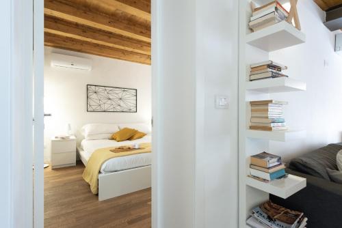 a bedroom with white walls and a bed and books at Ortigia Suite - Theater in Syracuse