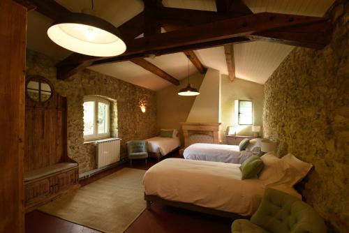 a bedroom with two beds in a room with stone walls at La Bastide Bleue in Séguret