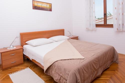 Schlafzimmer mit einem großen Bett mit einem Kopfteil aus Holz in der Unterkunft Apartmani MIRA in Premantura
