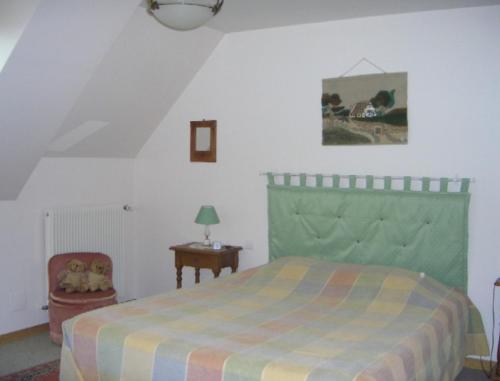 a bedroom with a bed with a green head board at Chambre d'hôtes La Cour in Rauville-la-Place