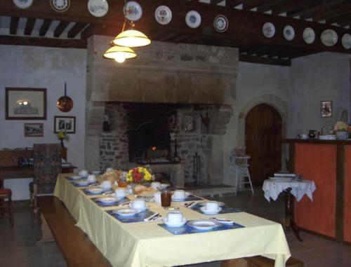 a table with plates on it in a room with a fireplace at Chambre d'hôtes La Cour in Rauville-la-Place