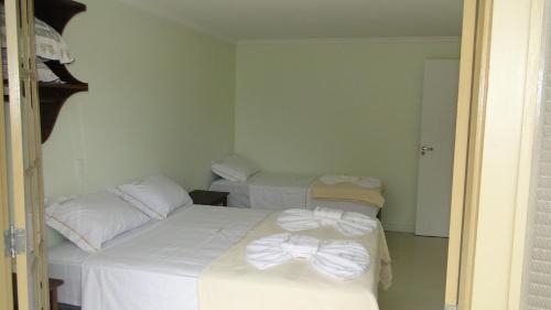 a room with two beds with white sheets and bows at Flats Martinez in Conservatória