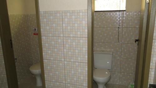 a bathroom with two toilets and a window and tiled walls at Flats Martinez in Conservatória