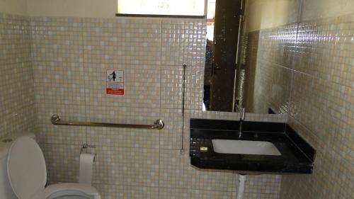 a tiled bathroom with a toilet and a sink at Flats Martinez in Conservatória