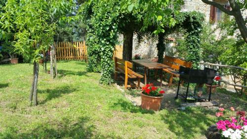 a garden with a bench and a table and flowers at Colonica Montebeni in Greve in Chianti