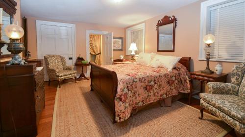 a bedroom with a bed and a chair and a mirror at Choctaw Hall Bed & Breakfast in Natchez
