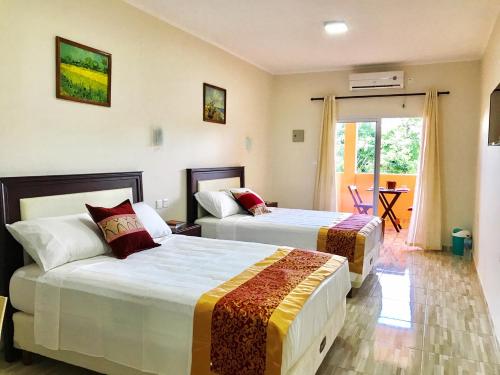 a hotel room with two beds and a balcony at Hotel Amayal in Puerto Iguazú
